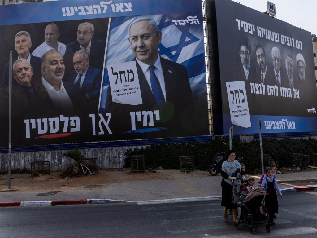 People walk next to a campaign banner of Netanyahu's Likud party in Bnei Brak, Israel (File Photo/Reuters)